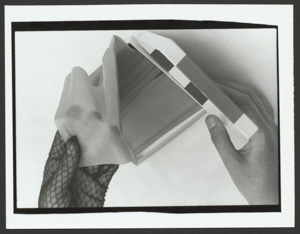 Susie Bright pulling a latex dental dam from a box with a hand gloved in black lace.